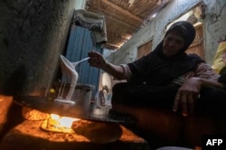 FILE - A woman prepares bread in her home at Zerzara village on the west bank of the Nile river, off of Egypt's southern city of Aswan, Feb. 26, 2022. Many fear Russia's invasion of Ukraine could mean less bread in Egypt, Lebanon, Yemen and elsewhere in t
