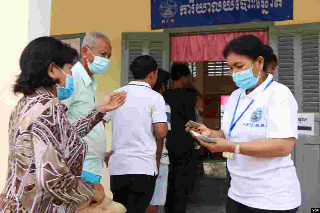 មន្ត្រី​តាម​ការិយា​ល័យ​បោះឆ្នោត​ ​ត្រួត​ពិនិត្យ​ឯក​សារ​បោះ​ឆ្នោត​របស់​ពល​រដ្ឋ​ នៅ​ការិយាល័យ​បោះ​ឆ្នោត​អូរ​តាគាំ១​​ ​ក្នុង​ក្រុង​បាត់​ដំបង នៅ​ថ្ងៃទី០៥ ខែមិថុនា ឆ្នាំ២០២២។ (លាស់ លីបលីប​/​វីអូអេ) 