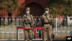 Chinese military personnel guard a road near the Tiananmen area where China's annual legislature meetings are held on March 8, 2022, in Beijing.