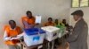 Funcionário de mesa de voto faz demonstração do boletim de voto a eleitor na Beira, Moçambique, 9 outubro 2024