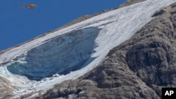 A rescue helicopter hovers over the Punta Rocca glacier near Canazei, in the Italian Alps in northern Italy, July 4, 2022, a day after a huge chunk of the glacier broke loose, sending an avalanche of ice, snow, and rocks onto hikers.