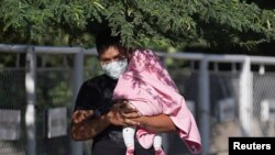 Un hombre con un bebé en brazos cruza el puente internacional Simón Bolívar, abierto solamente para asuntos humanitarios, en Cucuta, Colombia 7 de octubre de 2021.