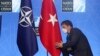 FILE - Seorang pejabat membetulkan letak bendera Turki menjelang berlangsungnya konferensi pers Presiden Turki Recep Tayyip Erdogan pada pertemuan puncak NATO di Brussels, 14 Juni 2021.