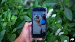 Maynor Cardona muestra una foto en su teléfono celular de su hija, Yenifer Yulisa Cardona Tomás, en el hospital en Texas, mientras recibe una visita.