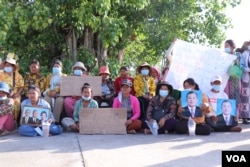 ប្រជាសហគមន៍សំរោងត្បូងរស់នៅជាប់បឹងតាមោក អង្គុយលើកបដា នៅទីធ្លាសួនវត្តបុទុមវត្តី ដើម្បីសុំអន្តរគមន៍ពីខុទ្ទកាល័យនាយករដ្ឋមន្ត្រី ក្នុងរាជធានីភ្នំពេញ កាលពីថ្ងៃទី២៩ ខែមិថុនា ឆ្នាំ២០២២។ (លាស់ លីបលីប/វីអូអេ)