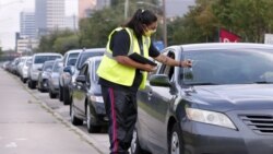 Volunteer Sharely Gomez marks the windshield after taking information from clients in their cars as they wait in line in before the food distribution begins at the West Houston Assistance Ministries Wednesday, Oct. 14, 2020, in Houston. (AP Photo/Michael