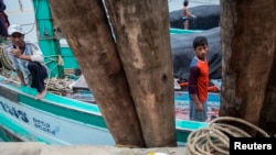 FILE - Migrant fishermen from Myanmar work on a boat after returning from the ocean to Ban Nam Khem, Thailand, Dec. 14, 2014. 