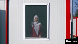FILE - A Syrian woman looks out of the window of a container home at a refugee camp in Harmanli, Bulgaria, Dec. 9, 2013. 