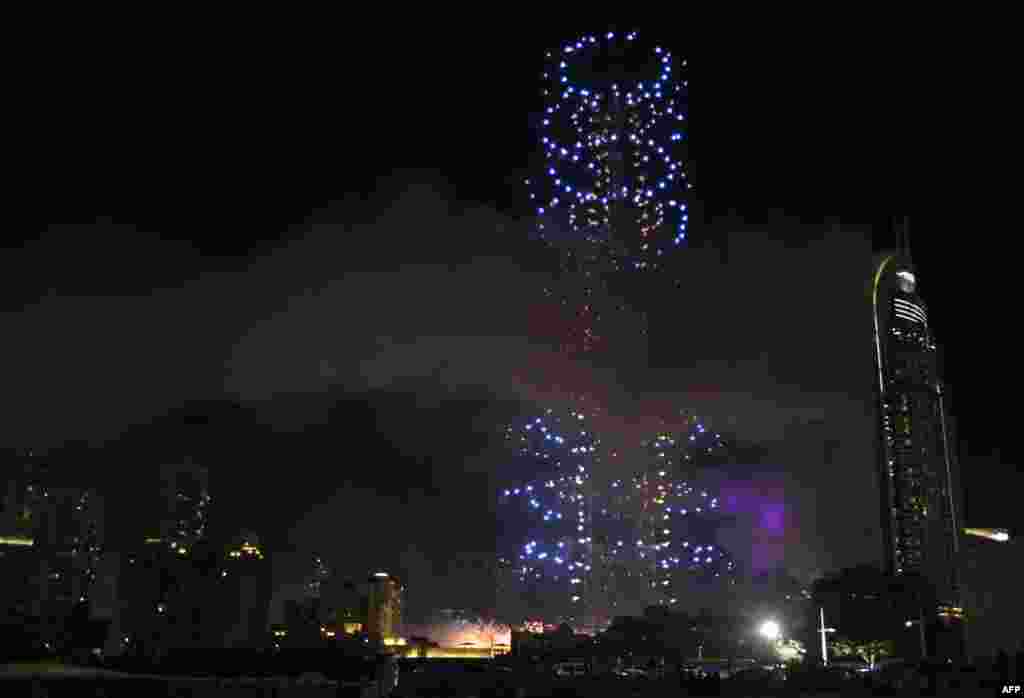 Fireworks explode during New Year's celebrations over Dubai's Burj Khalifa, the world's tallest tower, close to where flames were still billowing from the 63-story Address Downtown hotel, Jan. 1, 2016. Flames rip through the hotel after it was hit by a massive fire hours and more than a dozen people were injured.
