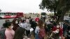 Migrantes escuchan a un voluntario en un estacionamiento después de ser detenidos y procesados ​​para solicitar asilo por parte de Estados Unidos. autoridades, viernes 12 de abril de 2024, en San Diego. (Foto AP/Gregory Bull)