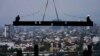 Trabajadores de la construcción viajan sobre una viga que cuelga de una grúa en el sitio de construcción de un edificio residencial de gran altura en la Ciudad de México, el 17 de junio de 2022.