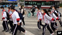 带着口罩的北京小学生穿过一条交通繁忙的十字路口。（美联社照片 2021年4月29日）