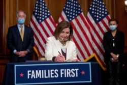House Speaker Nancy Pelosi, accompanied by Reps. Richard Neal, D-Mass., and Nydia Velazquez, D-N.Y., signs the Paycheck Protection Program and Health Care Enhancement Act, after it passed the House on April 23, 2020.