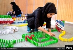 Young Iranian women set up a domino course.