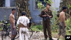 A North Korean soldier chats with a villager while doing a routine guard along the waterfront of the Yalu River at the North Korean town of Sinuiju, opposite side of the Chinese border city of Dandong, China, Saturday, Aug. 18, 2007.