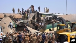 Wanajeshi na wafanyakazi wa kujitolea wakiwa katika eneo la ajali ya treni wilaya ya Ghotki kusini mwa Pakistan, Jumatatu, June 7, 2021, wakiendelea na zoezi la kuiondoa miili iliyokwama ndani ya mabaki ya treni.