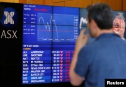 A man reacts in front of a board displaying stock prices at the Australian Securities Exchange (ASX) in Sydney, Australia, Nov. 9, 2016.
