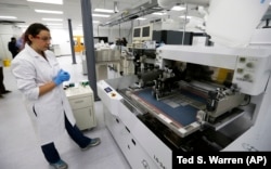 Caitlin Cramer, a PhD student in materials science engineering, demonstrates a machine that can produce electrical circuits and solar cells at the newly opened Washington Clean Energy Testbeds laboratory at the University of Washington.