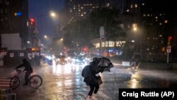 Wapita njia wakitafuta hifadhi karibu na eneo la Columbus Circle New York Jumatano, Septemba 1, 2021, wakati athari za Kimbunga Ida kikiendelea kwa kasi kilipokuwa kinapita upande wa ufuko wa bahari Mashariki.(AP Photo/Craig Ruttle)