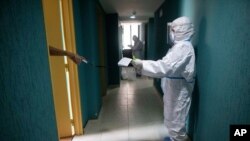 Un médico guarda distancia mientras hace lecturas de frecuencia cardíaca, presión arterial y oxigenación sanguínea de un paciente asintomático con COVID-19 en cuarentena en un hotel en Caracas, Venezuela. Julio 24, 2020.