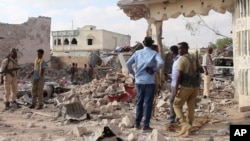 In this image taken from video on March 12, 2025, observers and security officers look over the aftermath of a car bomb explosion the previous day at a hotel in the central Somali city of Beledweyne.