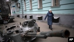 Una mujer camina junto a un tanque ruso destruido que se exhibe en una calle del centro de Kiev, Ucrania, el miércoles 25 de enero de 2023. (Foto AP/Daniel Cole)