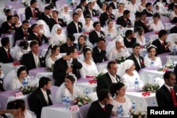 Brides and bridegrooms wait for the start of their wedding ceremony in Ankara, August 6, 2006.
