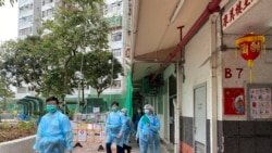 多名穿上保護衣的警員在康美樓出入口查詢出入的住客。(美國之音 湯惠芸拍攝)