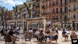 Customers sit and drink on a terrace bar in Tarragona, Spain, May 11, 2020. Roughly half of 47 million Spaniards are stepping into a softer version of the country's coronavirus strict confinement.