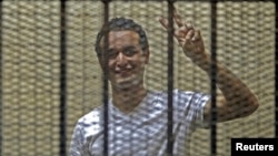 FILE - Egyptian activist Ahmed Douma gestures from behind bars at the New Cairo court, on the outskirts of Cairo.