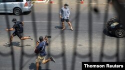 Pro-democracy protesters and a journalist run as riot police officers advance them during a rally against the military coup in Yangon