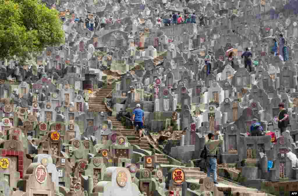 People attend to the tombs of relatives and friends during the Ching Ming Festival, also known as Tomb Sweeping Day, honoring the dead at a cemetery in Hong Kong.