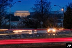 FILE - Traffic streaks along U.S. Highway 50 early in the morning, March 30, 2018, in Arlington, Va. The Trump administration announced April 2, 2018, that it would revise tough mileage standards for cars and light trucks, saying Obama-era rules were "not appropriate."