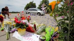 A man kneels at a make-shift memorial at the site of the police shooting of Philando Castile in Falcon Heights, Minnesota, July 7, 2016.