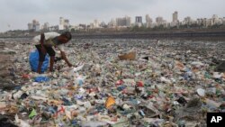 FILE - A man collects plastic and other recyclable material from the shores of the Arabian Sea, littered with plastic bags and other garbage, in Mumbai, India, June 4, 2018.