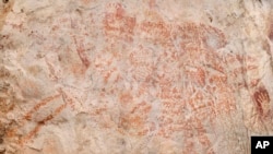 This composite image from the book "Borneo, Memory of the Caves" shows the world's oldest figurative artwork dated to a minimum of 40,000 years, in a limestone cave in the Indonesian part of the island of Borneo. (Luc-Henri Fage/kalimanthrope.com via AP)