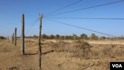 Wires of a fence are propped up in order for herders’ livestock to pass through into Mugie Conservancy, Laikipia, Kenya, March 17, 2017. (J. Craig/VOA)