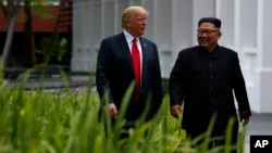 President Donald Trump walks with North Korean leader Kim Jong Un on Sentosa Island, June 12, 2018, in Singapore. 