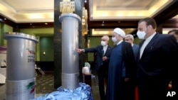 Rais wa Iran Hassan Rouhani (wapili kutoka kulia) anamsikiliza mkuu wa Taasisi ya Atomic ya Iran Ali Akbar Salehi alipokuwa akitembelea kuona maonyesho ya mafanikio ya nyuklia huko Tehran, Iran.