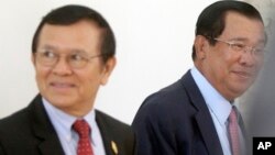 Cambodia's Prime Minister Hun Sen, right, walks with opposition Cambodia Rescue Party Deputy President Kem Sokha, left, during a break at National Assembly in Phnom Penh, Cambodia, Wednesday, Dec. 7, 2016. Cambodia's newly pardoned Kem Sokha has returned to parliament with a claim that he and Prime Minister Hun Sen have agreed to help reconcile their contending parties for the sake of benefiting the country. (AP Photo/Heng Sinith)