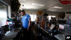 Brian Boyd peers out the window of the darkened Clear Creek Crossing store near Paradise, Calif., Oct. 24, 2019. 