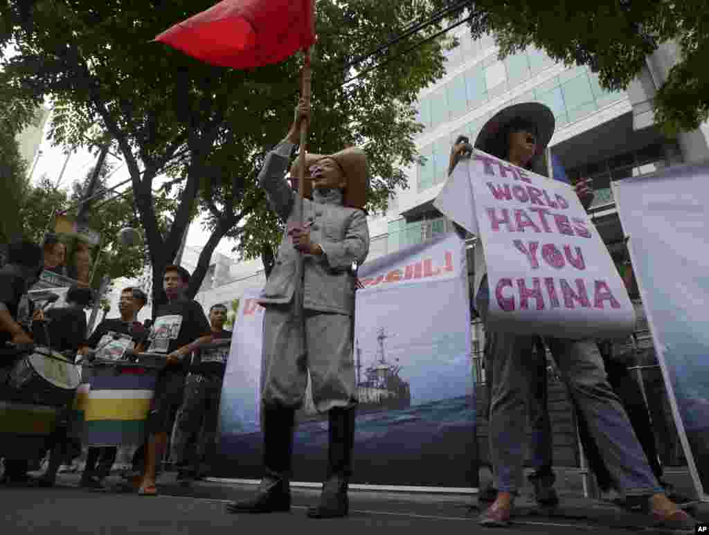 Protesters display placards while shouting slogans outside the Chinese Consulate in Manila against China's construction in a disputed area of the South China Sea, June 12, 2014.
