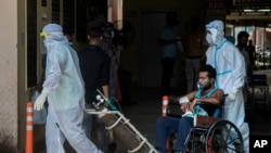 Petugas kesehatan mengenakan APB memindahkan pasien COVID-19 di sebuah rumah sakit pemerintah di Gauhati, India, Senin, 24 Mei 2021. (Foto: AP)