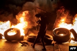 Demonstrant hoda pored zapaljenih guma u okupiranoj teritoriji na Zapadnoj pobali, 27. novembra 2023, pred očekivano oslobađanje palestinskih zatvorenika u zamenu za oslobađanje izraelskih talaca koje drži Hamas.