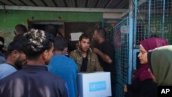 Los palestinos reciben ayuda distribuida por la UNRWA, la agencia de la ONU que ayuda a los refugiados palestinos, en el campo de refugiados de Nusairat, Gaza, el martes 5 de noviembre de 2024. AP