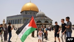 مسجد الاقصی کے سامنے چند فلسطینی نوجوان اپناپرچم لہرا رہے ہیں۔ 21 مئی 2021
