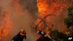آتش‌نشانان در حال مبارزه با آتش‌سوزی جنگلی در روستایی در جزیره ائوبویا در ۱۷۶ کیلومتری شمال آتن، یونان - ۱۸ مرداد ۱۴۰۰
