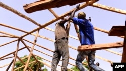 Les charpentiers assemblent des poutres en palmier de la charpente d'une maison en pisé, dans le village de Toubakouta, à 9 kilomètres au sud de Ziguinchor, dans la région sud de la Casamance, près de la frontière avec la Guinée-Bissau le 12 mai 2017.