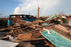 FILE - A rainbow rises over the extensive damage and destruction in the aftermath of Hurricane Dorian in The Mudd, Great Abaco, Bahamas, Sept. 5, 2019.
