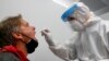 An employee of a new Lufthansa corona quick test center takes a test of a man at the airport in Munich, Germany, Nov. 12, 2020. 